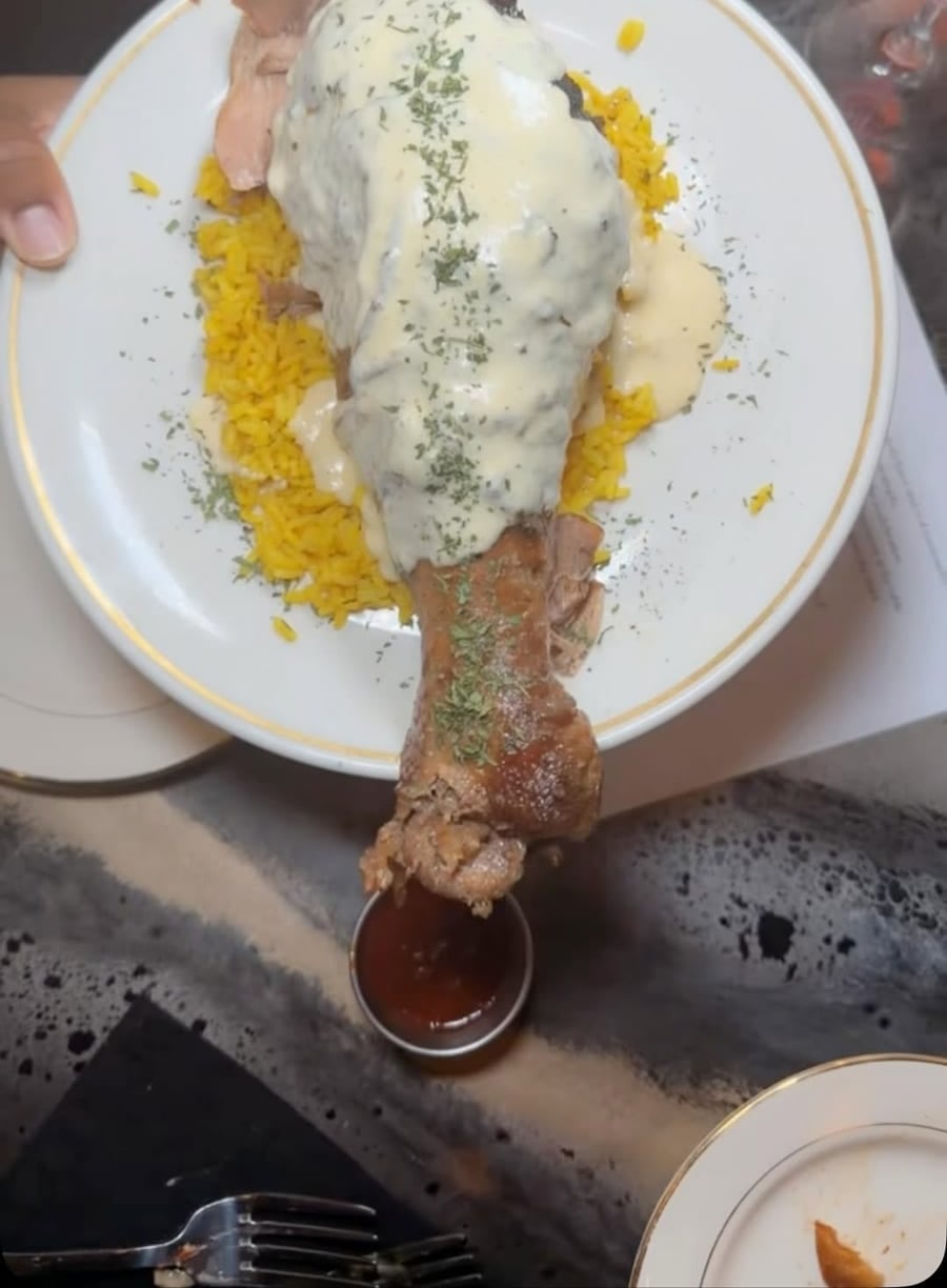 A signature plate of grilled protein over rice with a rich cream sauce